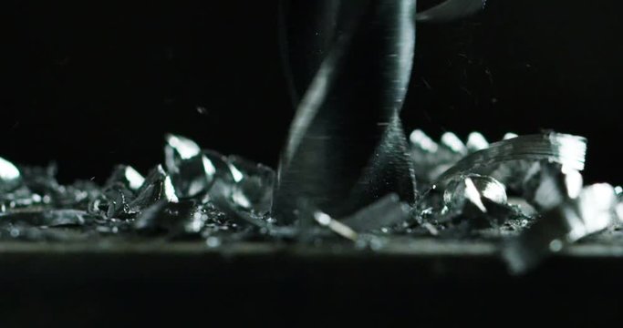 Macro shot of a drill that pierces a sheet of iron or steel. The tip of the metal drill with a circular motion pierces the material. Concept:engineering,industry,technology, locksmith and construction
