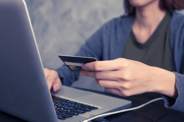 Close up of female hand holding credit card and using laptop 