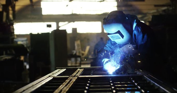 .A blacksmith or welder, with his welder, welding steel and iron, in extreme slow motion. The welder uses a mask to protect your eyes from sparks. concept: manual work, blacksmith, industry, welder