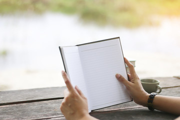 Stock Photo:.Woman hands holding the open book on Natural backgr