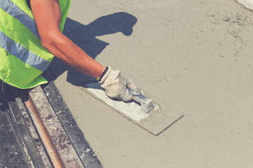 Construction worker leveling concrete pavement.