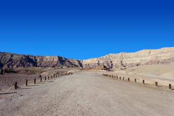 Empty desert road with mountains and blue sky in the background