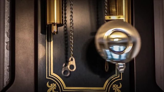 The pendulum of the old clock with the battle close up.
