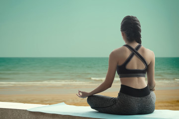 Fototapeta na wymiar young woman practicing yoga on the beach.