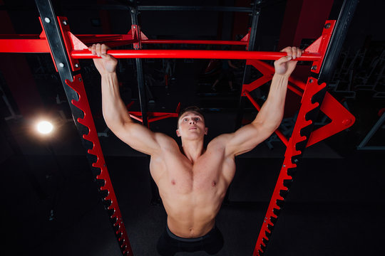 Strong man doing pull ups handsome athlete at gym. big confident muscular  training.