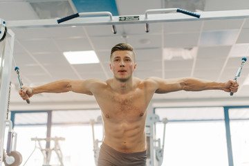 close up photo of attractive man training on Fitness-station. Guy with six-pack abs and strong...