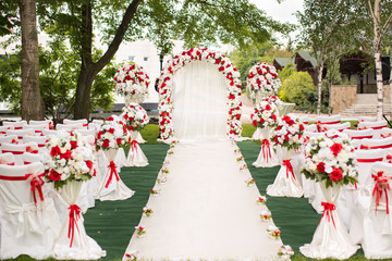 Wedding ceremony outdoors. Wedding arch decorated with red flowe