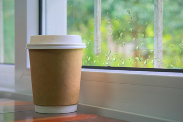Paper coffee cup placed near the window.