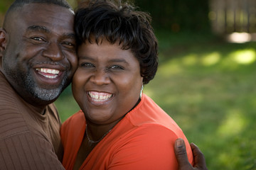 Mature African American couple laughing and hugging.