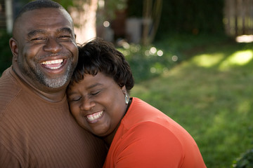 Mature African American couple laughing and hugging.
