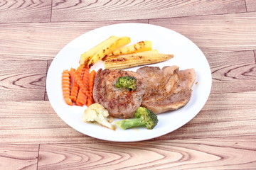 Pork steak with mixed vegetable on white dish.