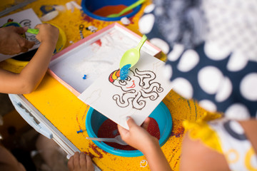 A child draws with colored sand picture. Cartoon characters.