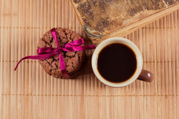 Top view on the cup of coffee cookies with tape and old retro book.