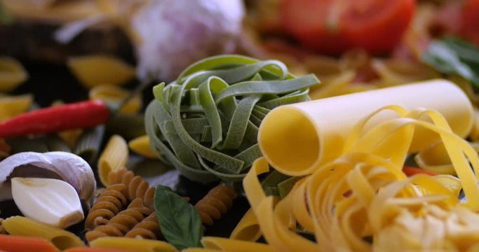 Dolly extreme close up view of different variety of Italian pasta and ingredients