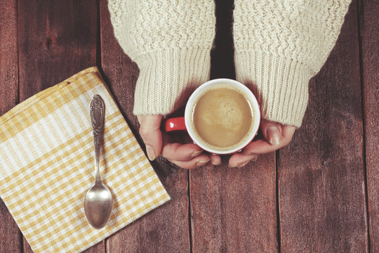 Cozy mood with coffee in sweet home. Girls hands with cup of coffee at the wooden table.