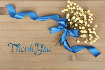 The inscription thank you on the background of a decorative flower with ribbon.