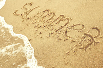 Summer inscription on the sand at the beach as concept of family vacations at the sea