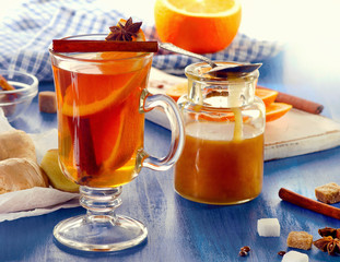 Ginger tea with orange and honey in glass cup.