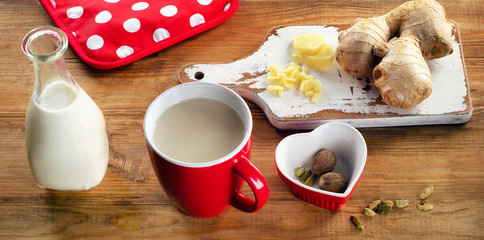 Ginger tea with milk in a cup on  wooden table.