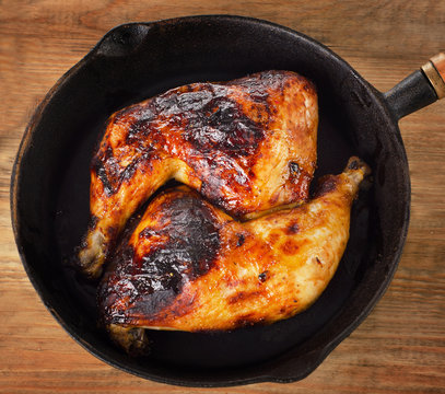 Roasted chicken legs on a cast iron skillet.