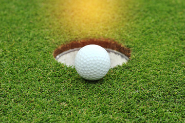 golf ball near the hole on green grass
