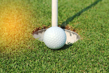 golf ball near the hole on green grass