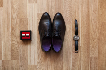 Black shoes, watch and cufflinks on the floor. Accessories for t