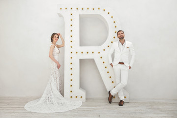 Chic wedding couple groom and bride posing in a white Studio. Ha