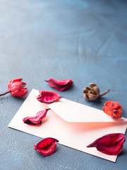 Pink envelope with dried flowers petals on dark blue background. Valentine's day. Sending Love letter