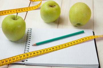 Green apples with measuring tape on a white wooden table