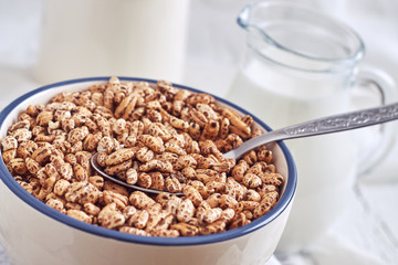 Puffed barley cereal in bowl with pitcher of milk in background
