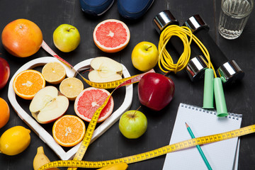 Diet plan, fruits and centimeter on a black background