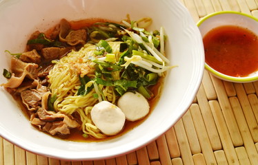 Chinese yellow noodle topping braised pork in brown soup and spicy chili sauce