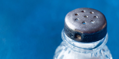 Vintage salt bottle on dark blue background. Macro texture detail banner