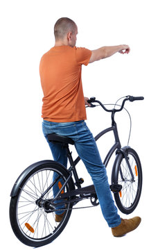 back view of pointing man with a bicycle. cyclist sits on the bike.  Rear view people collection.  backside view of person. Isolated over white background. Shorthair guy on the bike led shows hand up.
