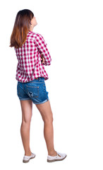 back view of standing young beautiful  woman.  girl  watching. Rear view people collection.  backside view of person.  Girl in shorts and a plaid shirt looking sideways with his arms crossed.