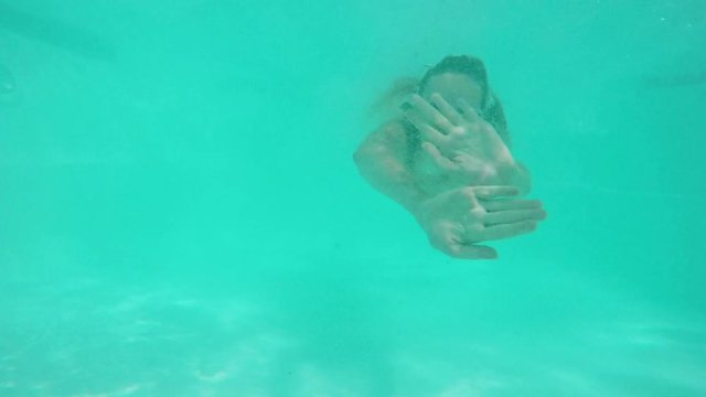 Beautiful blonde female in black swimsuit jumping into pool swimming smiling laughing. Underwater footage in slowmotion