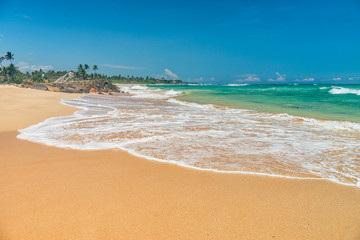 Fototapeta na wymiar Sunny beach near Koggala - Sri Lanka. Waves of clear water and warm sand 