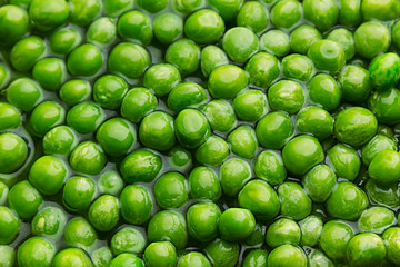 Wet fresh green peas in water closeup as background. Healthy vitamin food.