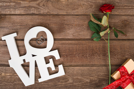 Box with red ribbon and rose on a wooden background, Valentine's Day concept