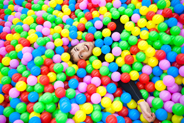 Fototapeta na wymiar Happy and funny young man relaxing in many colorful balls 