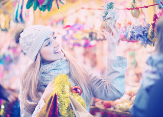 Young positive  woman at fair near counter with Christmas gifts