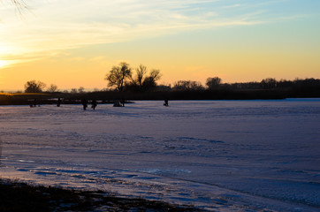 Winter fishing on frozen river Dnieper at sunset