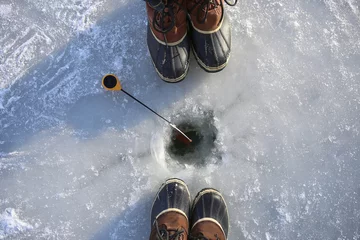 Fotobehang Ice fishing on frozen lake. Two people fishing together. Ice hole, winter rod and boots. © vaitekune