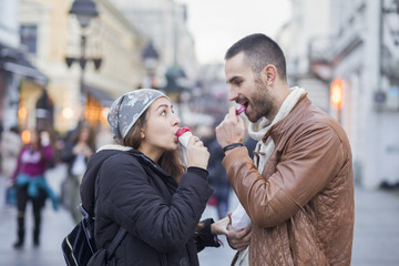 Young couple in love in the city walks eating ice cream on stree