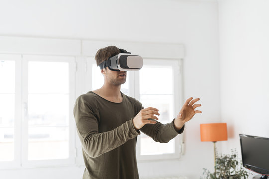 Young man wearing virtual reality glasses at home