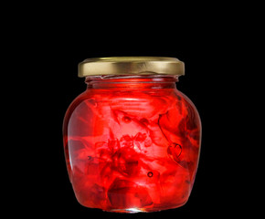 Jam of rose petals in a glass jar on a black background.