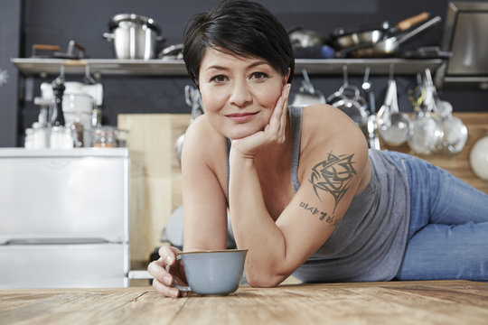 Portrait of smiling woman in kitchen with cup of coffee