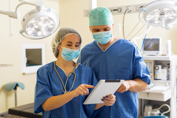 Doctor and his assistant using tablet in surgery room