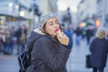 Young woman eating ice cream in the city. Shallow depth of field